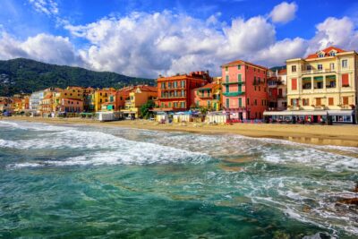destination de longe-côte. Mer agitée de vagues légères face à un village côtier italien coloré, offrant un superbe spot de longe-côte entre sport et patrimoine.